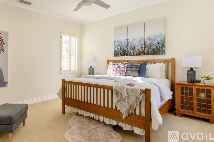 A bedroom with a large bed, a bench, and a painting on the wall.