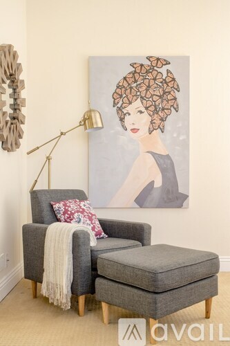 A grey chair with a pillow and a blanket on it.