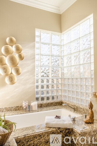 A bathroom with a tub, a window, and a wall decoration.