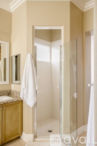 A white towel hangs on a glass door in a bathroom.