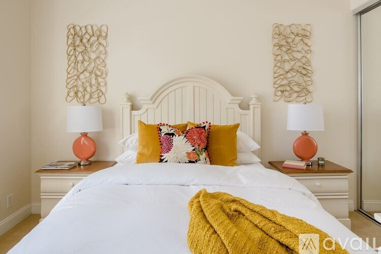 A bedroom with a white bed and two lamps on either side.