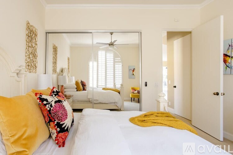 A bedroom with a bed, a couch, and a mirror.