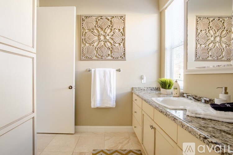 A bathroom with a marble countertop and a decorative wall hanging.