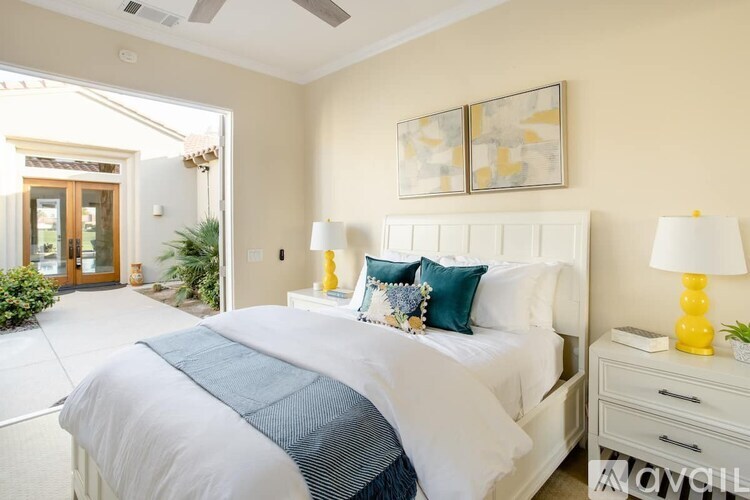 A bedroom with a white bed and a painting on the wall.