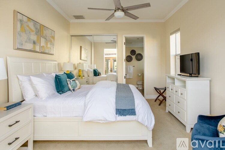 A bedroom with a large bed, a television, and a ceiling fan.
