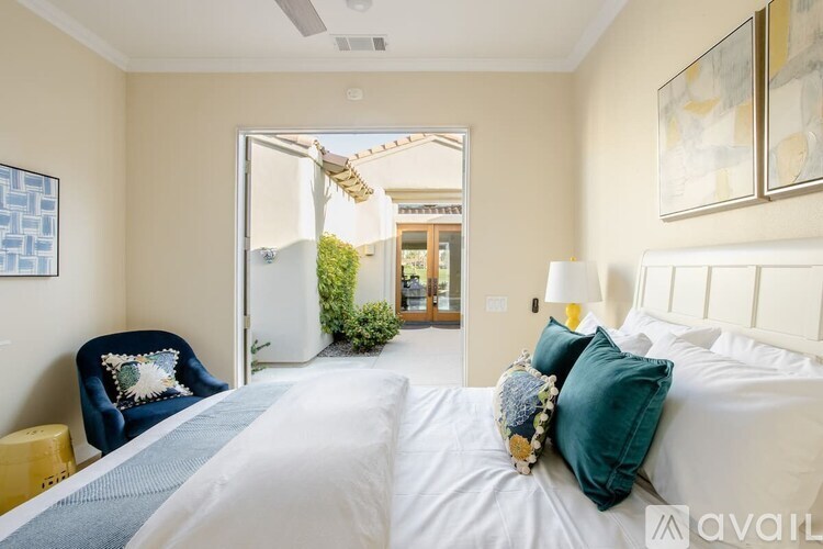 A bedroom with a large bed and a blue chair with a pillow on it.