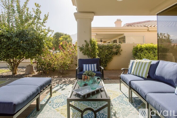 A blue couch and chair are on a patio with a table in between.