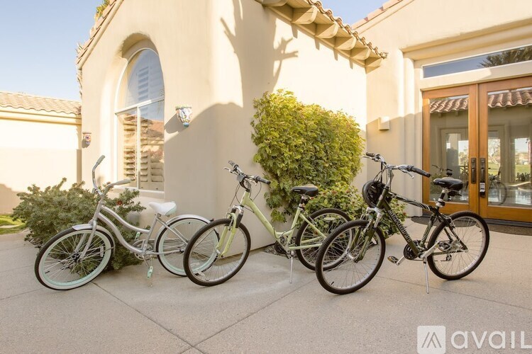 Two bicycles are parked in front of a building with a sign that reads "available.".