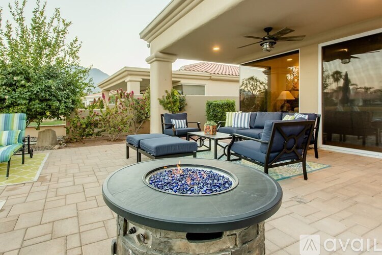 A patio with a fire pit and chairs.