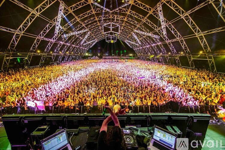 A DJ mixes music in front of a large crowd at a concert.