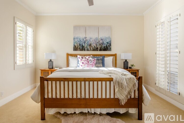 A bedroom with a large bed and a painting on the wall.