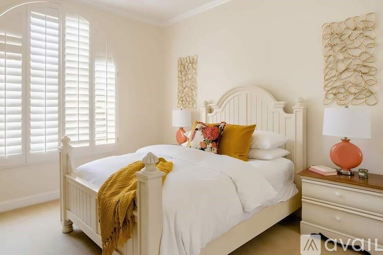 A bedroom with a white bed and a yellow throw on it.