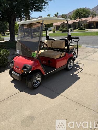 A red golf cart is parked on a driveway.