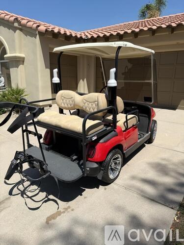 A red and black golf cart with a tan seat and canopy.