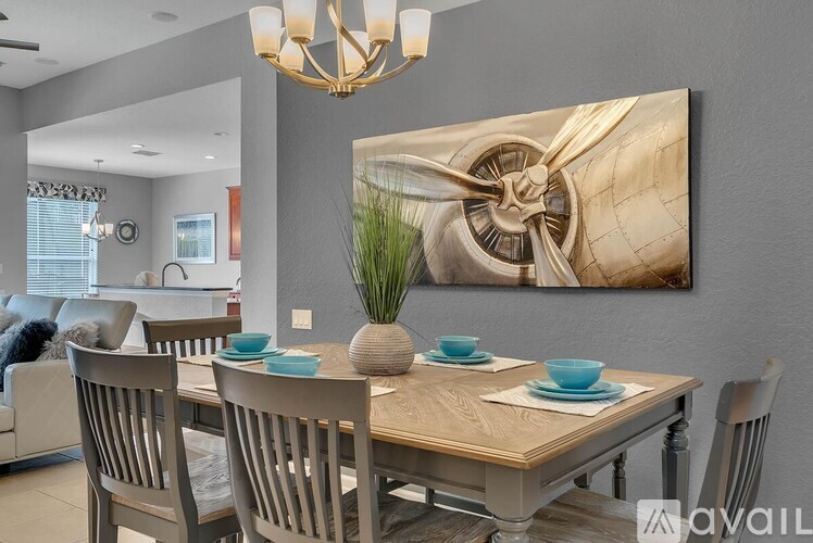 A dining room with a wooden table and chairs, a chandelier, and a large painting on the wall.