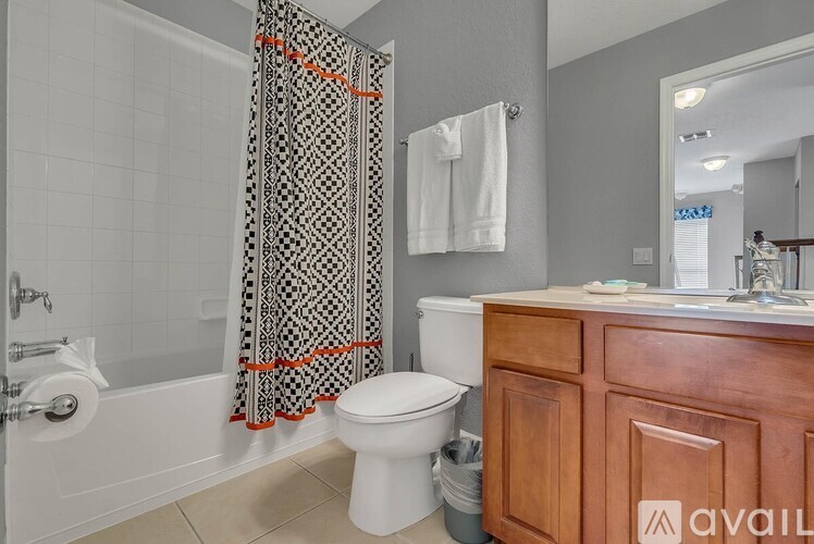 A bathroom with a toilet, a shower curtain, and a wooden cabinet.