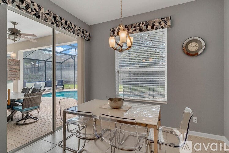 A dining room with a glass table and chairs, a ceiling fan, and a window with blinds.