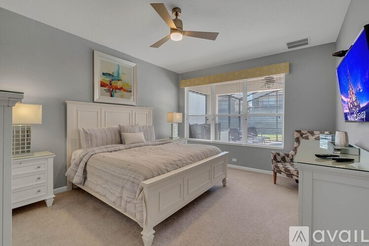 A bedroom with a large bed, a ceiling fan, and a chair.