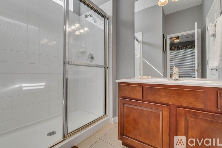 A bathroom with a glass shower door and a wooden vanity.