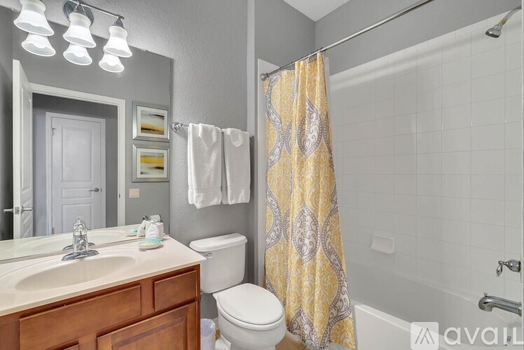 A bathroom with a white toilet, a sink, and a shower with a yellow shower curtain.