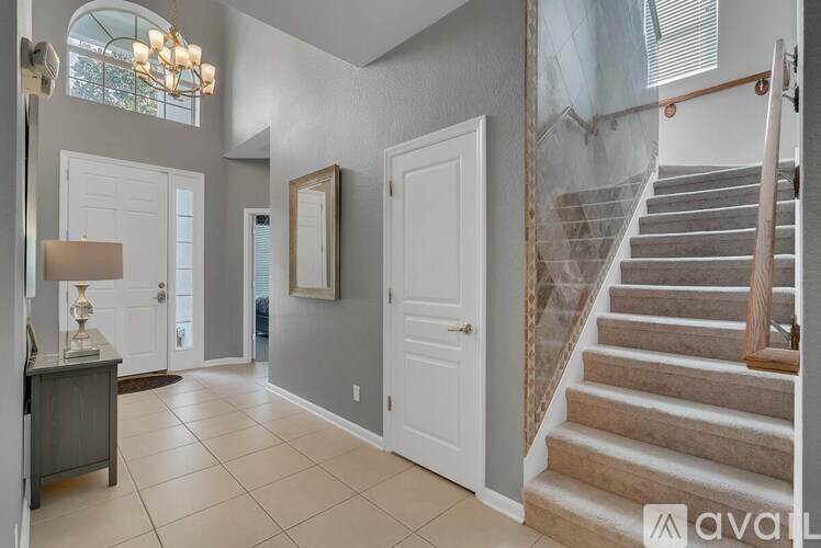 A hallway with a staircase and a lamp on a table.