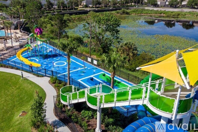 A water slide with a yellow umbrella is in the foreground of a pool.