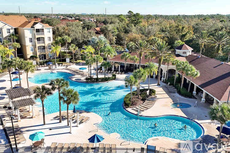 A large pool surrounded by palm trees and a resort.