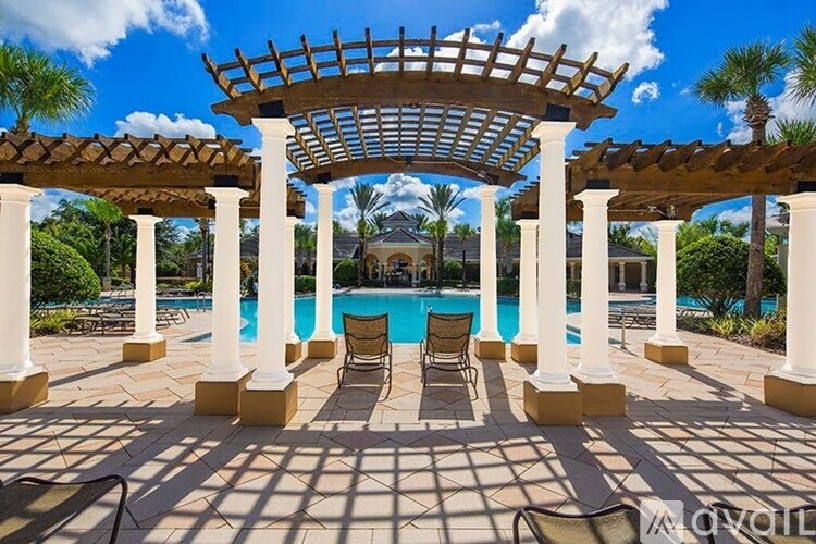 A pool area with a pergola and lounge chairs.