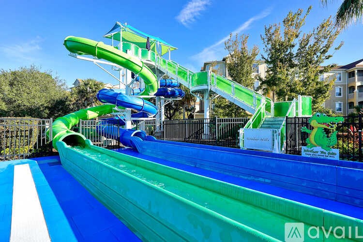 A water slide with a green and blue slide and a white and blue striped pool.
