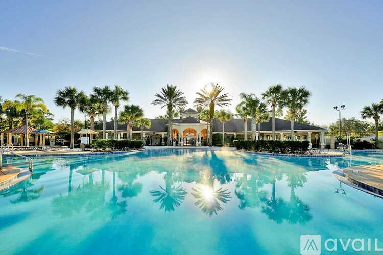 A large swimming pool with palm trees and a building in the background.