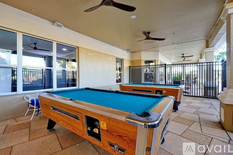 A pool table with a green felt cloth is in the foreground of an outdoor patio area.