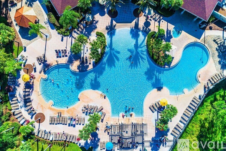 An aerial view of a resort with a large swimming pool and surrounding greenery.