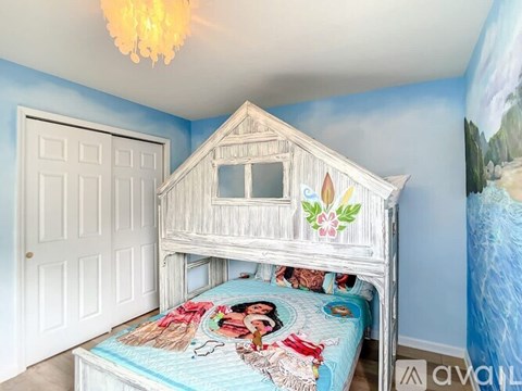 A child's bedroom with a white bed and a blue wallpapered wall.