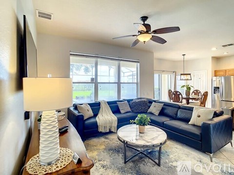 A living room with a blue couch and a white lamp.