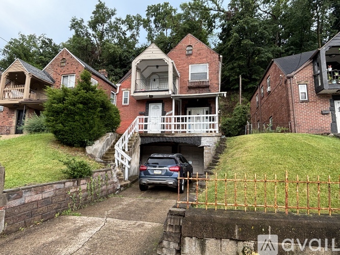 A car is parked in front of a house with a garage.