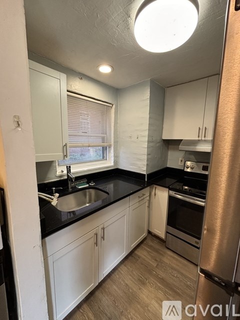 A kitchen with white cabinets and a black countertop.
