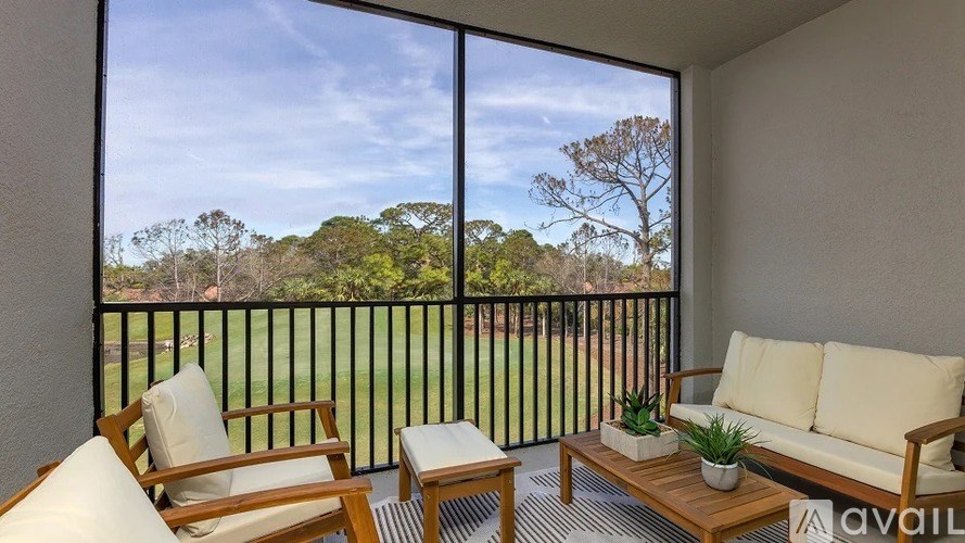 A balcony with a couch, chair, and table with a view of trees.