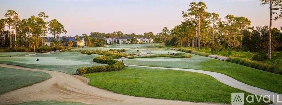 A golf course with a sand bunker in the foreground and trees in the background.