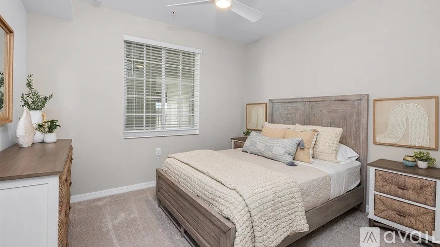 A bedroom with a bed, nightstand, and a window with blinds.