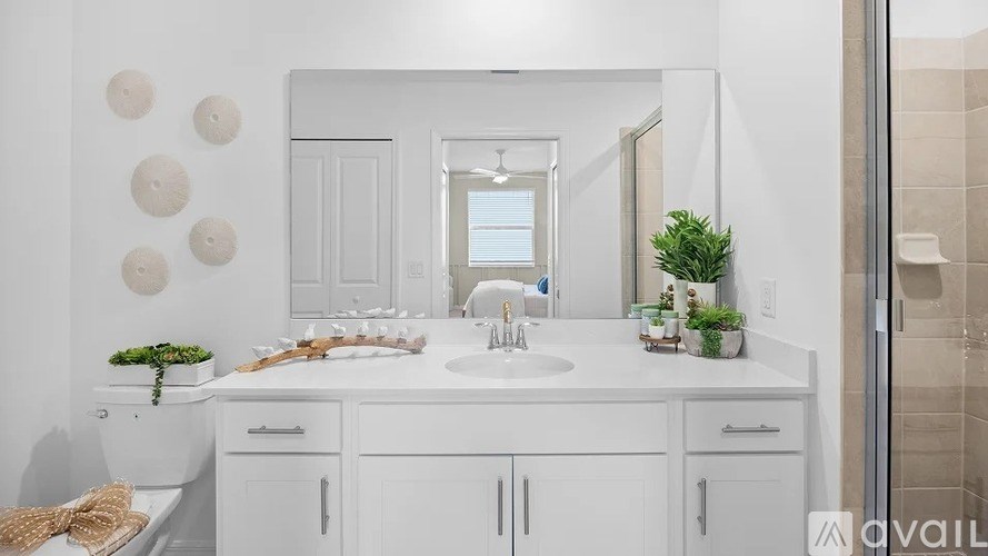 A white bathroom with a sink, mirror, and toilet.