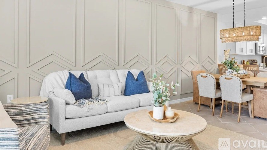 A living room with a white couch and blue pillows.