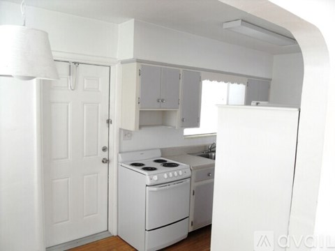 A white kitchen with a stove, oven, and cabinets.
