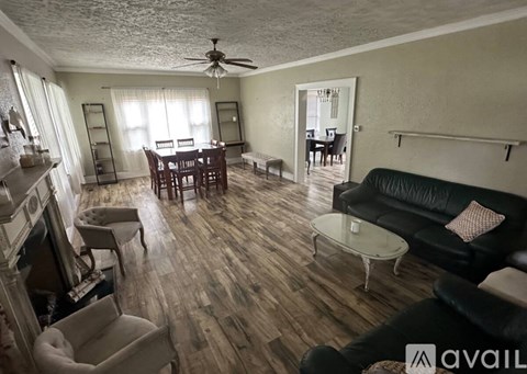 A living room with a black couch and a wooden floor.