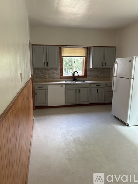 A kitchen with a white refrigerator and wooden cabinets.