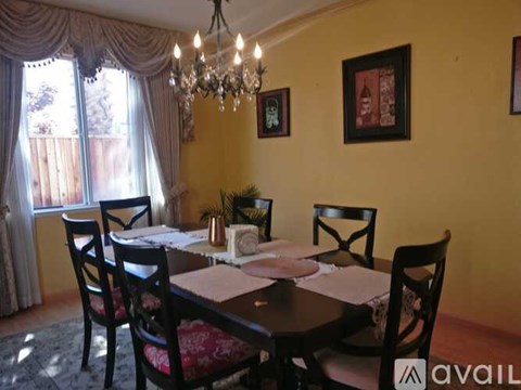A dining room with a table set for two and a chandelier.