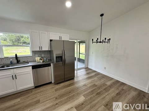 A kitchen with white cabinets and a wooden floor.