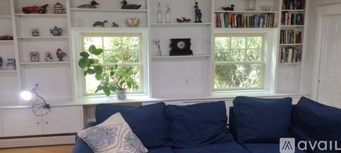 A living room with a blue couch and a window.