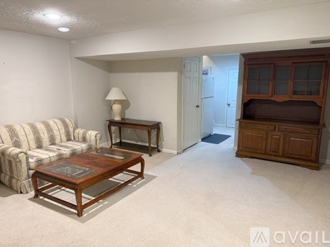 A living room with a striped sofa, a wooden coffee table, and a wooden side table with a lamp.