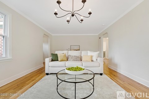 A living room with a white couch and a chandelier.