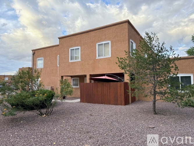 A modern house with a brown fence and a gravel driveway.